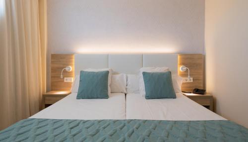a bedroom with a bed with two blue pillows at Leonardo Royal Hotel Ibiza Santa Eulalia in Es Cana