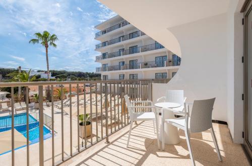 a balcony with a table and chairs and a pool at Leonardo Royal Hotel Ibiza Santa Eulalia in Es Cana