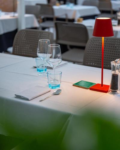 a table with a red lamp and glasses on it at Hotel San Teodoro in San Teodoro