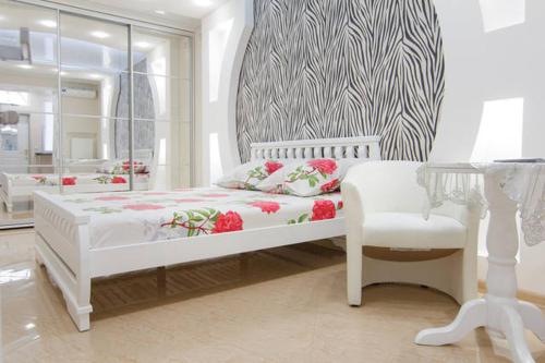 a white bedroom with a bed and a chair at Apartment on Sadovaya in Odesa
