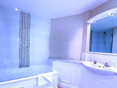 a bathroom with a tub and a sink and a mirror at The Grand Hotel in Torquay