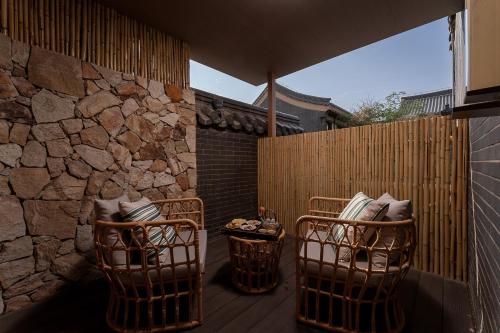 een patio met 2 stoelen en een stenen muur bij Huazhu Luxurious Mountain Courtyard Private Hot Spring Resort in Longmen