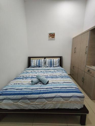 a bedroom with a bed with a blue and white blanket at Bertam Wawasan Homestay in Kepala Batas