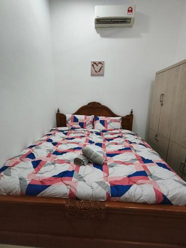 a bed with a colorful quilt on it in a bedroom at Bertam Wawasan Homestay in Kepala Batas