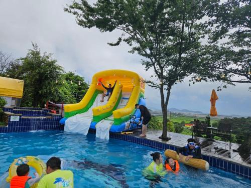 a group of people in a swimming pool with a water slide at Nobless Pension in Taean