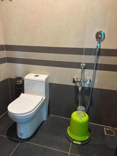 a bathroom with a toilet and a green container at Cure Monastery Family Resort in Marayoor