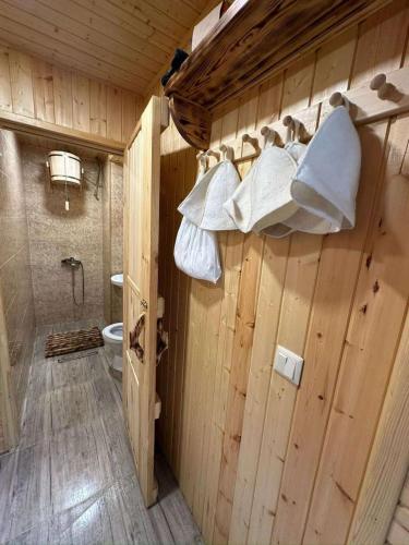 a wooden bathroom with a toilet and towels on the wall at Villa Dejaviu Dilijan in Dilijan