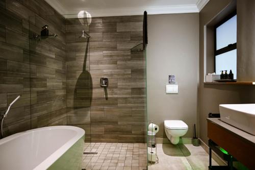 a bathroom with a tub and a toilet and a sink at Silver Forest Boutique Hotel and Spa in Somerset West