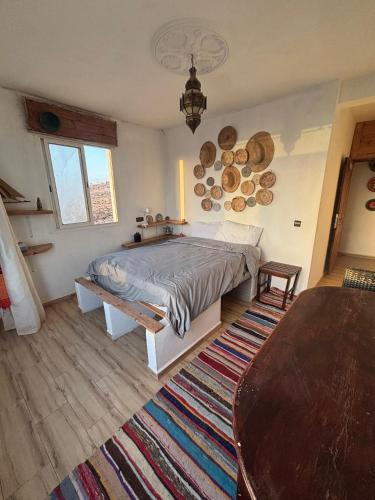 a bedroom with a bed with a table and a rug at EL Faro Surfstay in Tamri