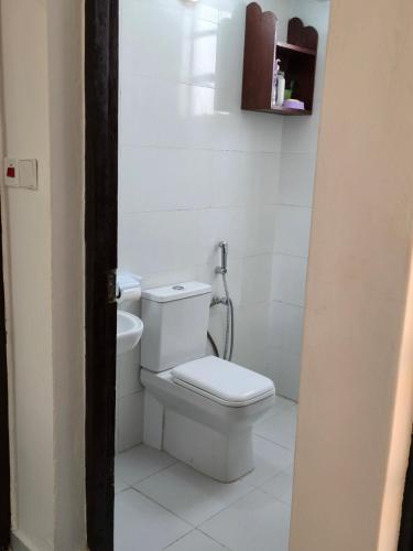 a bathroom with a toilet in a white room at Charming chalet Diani in Diani Beach