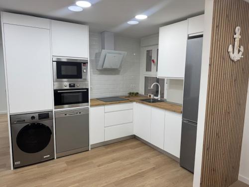 a kitchen with white cabinets and stainless steel appliances at Mar de Ría 2 in Ribeira