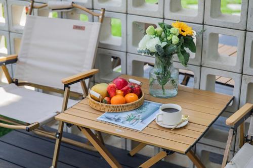 un tavolo con un cesto di frutta e un vaso di fiori di Qingcen Manor a Chiyu