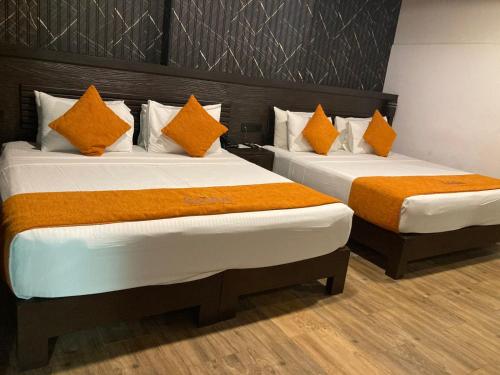 two beds in a hotel room with orange pillows at Sasha Transit Hotel in Katunayake