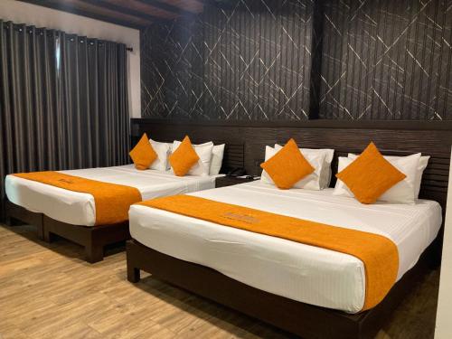 two beds with orange and white pillows in a room at Sasha Transit Hotel in Katunayake