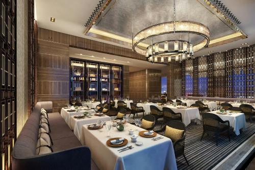 a restaurant with white tables and chairs and a chandelier at JW Marriott Hotel Xi'an in Xi'an