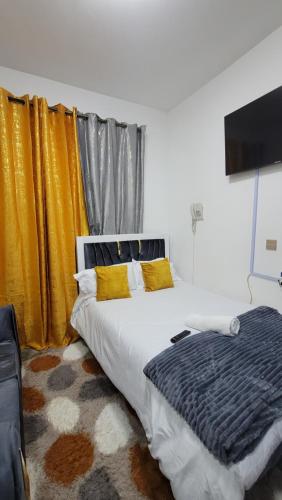 - une chambre avec un grand lit et des rideaux jaunes dans l'établissement Jakima studios Ruaka, à Ruaka