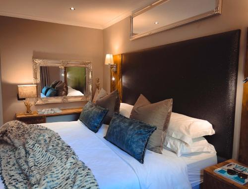 a bedroom with a large white bed with pillows and a mirror at Silver Forest Boutique Hotel and Spa in Somerset West