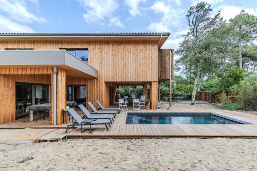 a house with a swimming pool and a deck at Villa 10 pers à Carreyre, piscine chauffée, clim in Lacanau