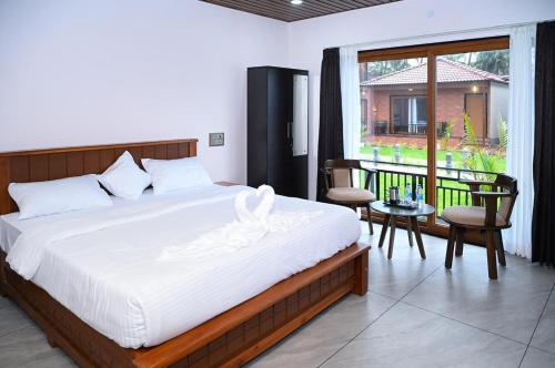 a bedroom with a large white bed and a balcony at Shivani Sunset Bay Beach Resort in Māvalli