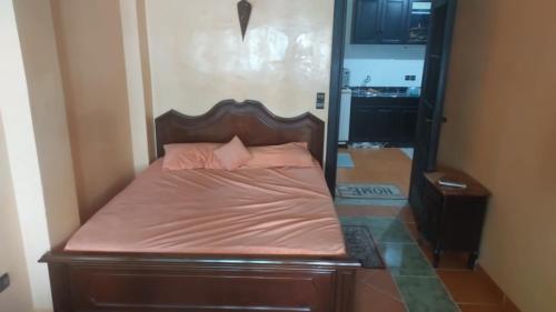 ein Bett mit einem hölzernen Kopfteil in einem Zimmer in der Unterkunft La gare agdal in Rabat