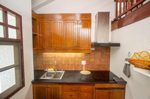 a kitchen with wooden cabinets and a stove top oven at Triple Trees A15 House Khao Yai in Mu Si