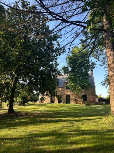 an old stone house with trees in the foreground at Songe de Clarté in Plouigneau
