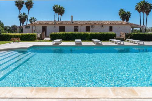 a swimming pool in front of a house with palm trees at 3 Twins Suite Portopalo in Portopalo