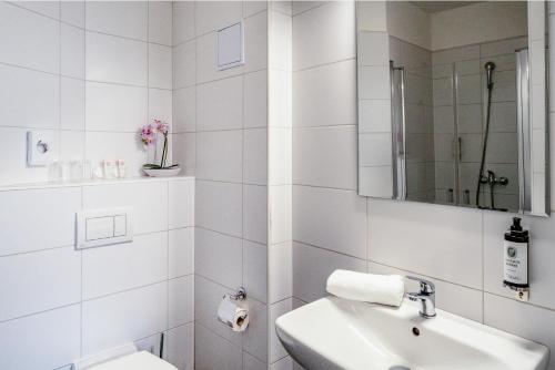 a white bathroom with a sink and a mirror at BlueBell Hotel in Bratislava