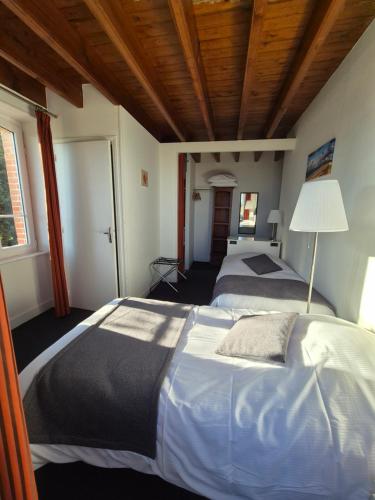 a bedroom with a large bed with a wooden ceiling at La Roche du Marais in Omonville-la-Petite