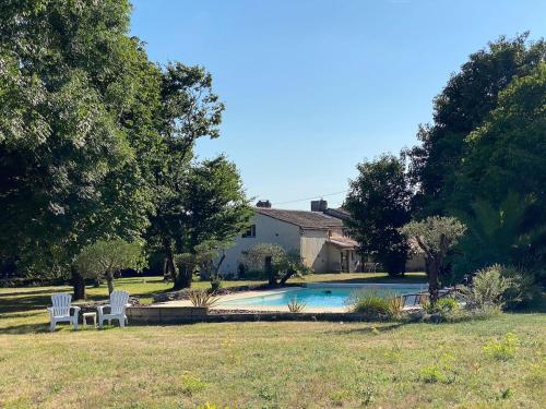 a yard with two white chairs and a swimming pool at Gite avec piscine et grand jardin in Saint-Simon-de-Pellouaille