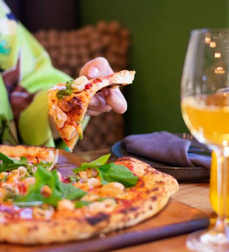 a person eating a slice of pizza with a glass of wine at Silver Forest Boutique Hotel and Spa in Somerset West