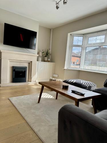 a living room with a coffee table and a fireplace at Ruby's Home in Wistaston