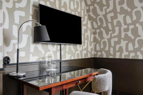 a room with a desk with a tv on a wall at Grand Halmstad, WorldHotels Crafted in Halmstad