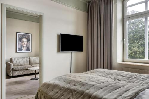 a bedroom with a bed and a couch and a television at Grand Halmstad, WorldHotels Crafted in Halmstad