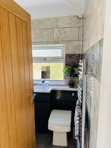 a bathroom with a toilet and a sink and a window at Ruby's Home in Wistaston