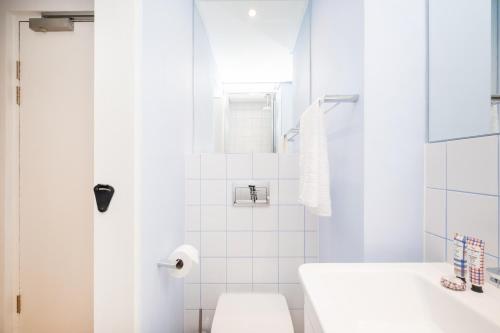 a white bathroom with a toilet and a shower at 1007 Zeeland - Top Floor Stylish Studio Near CTICC in Cape Town