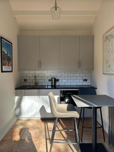 a kitchen with white cabinets and a table and chairs at The Gatehouse in Trimingham