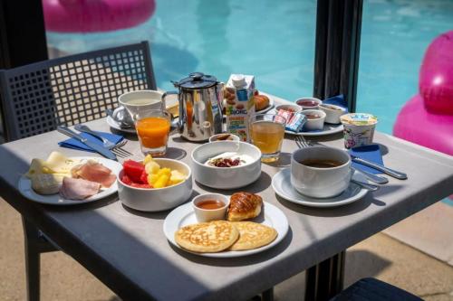 a breakfast table with breakfast foods and coffee on it at Hotel Caiman in Pierrelatte