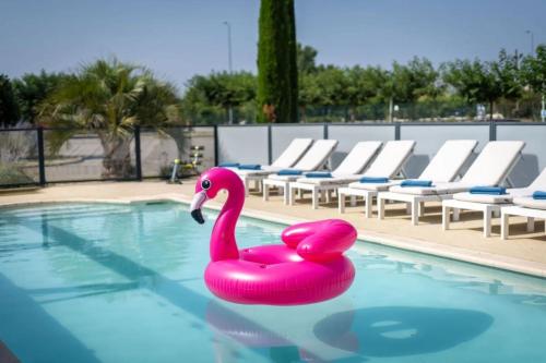 a pink swan float in a swimming pool at Hotel Caiman in Pierrelatte