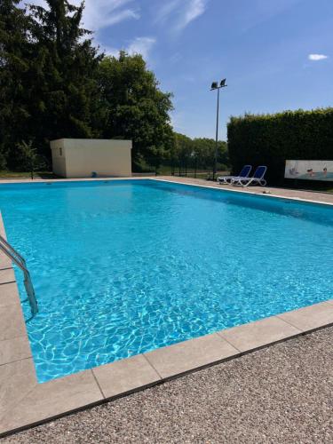 a large blue swimming pool with two chairs in it at Camping de Saulieu in Saulieu