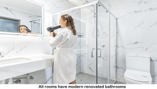 a woman in a bathroom blow drying her hair at Aaron Motel in Gladstone