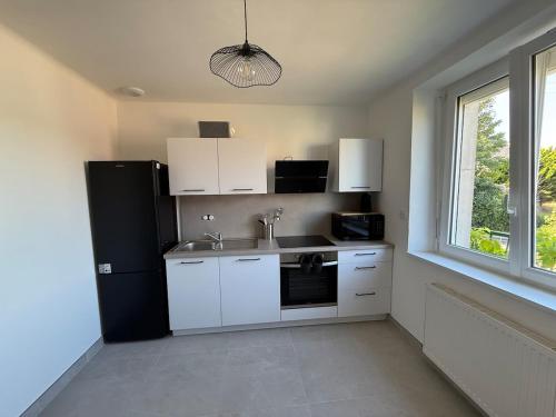 a kitchen with white cabinets and a black refrigerator at Maison refaite à neuf avec jacuzzi - LE HOMARD 13 in Perros-Guirec