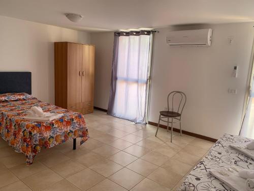 a bedroom with a bed and a chair and a window at Sofis Servizi Rio Grande (CAV) in Principina a Mare