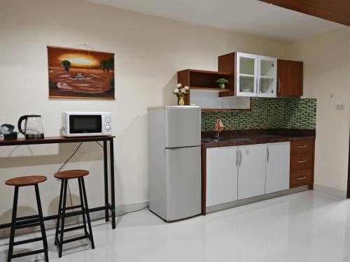 a kitchen with a refrigerator and a table and stools at Phratamnak Grand Apartments - Cozy Beach in Pattaya South