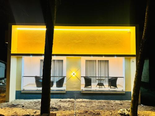 a yellow house with a table and chairs at Sooru The Beach Stay in Padubidri