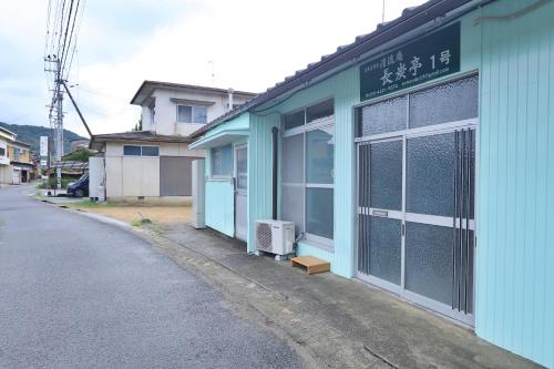 a blue building with a sign on it next to a street at まんのう清流庵 in Manno