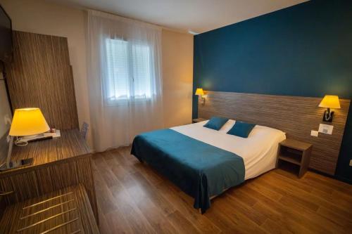 a bedroom with a large bed with a blue headboard at Hotel Caiman in Pierrelatte