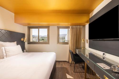 a hotel room with a bed and a flat screen tv at EVE Eilat by Adam Hotels in Eilat