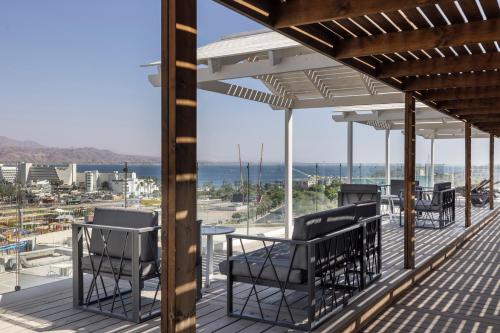 a deck with chairs and a table and a view of the ocean at EVE Eilat by Adam Hotels in Eilat