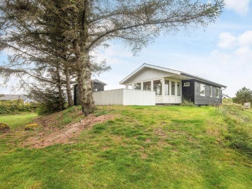 a house on top of a hill with a tree at 6 person holiday home in Rømø in Bolilmark
